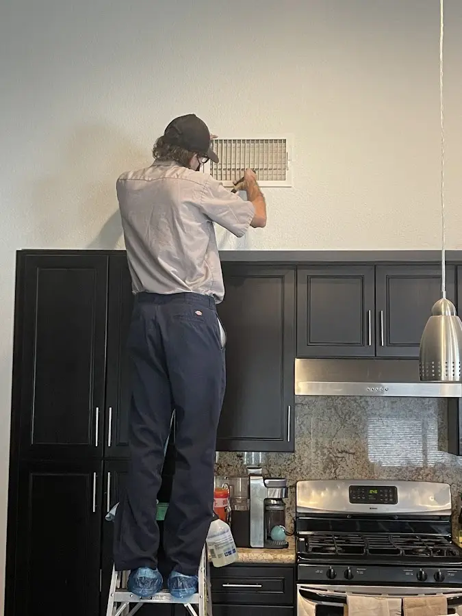 Technician inspecting an air vent during HVAC service in Plattsburgh
